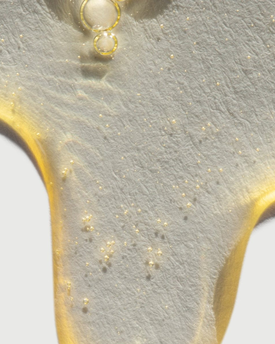 A close-up of the taïla MUHKA Botanical Cleanser texture emulsifying from a rich oil into a smooth, white milky lotion.