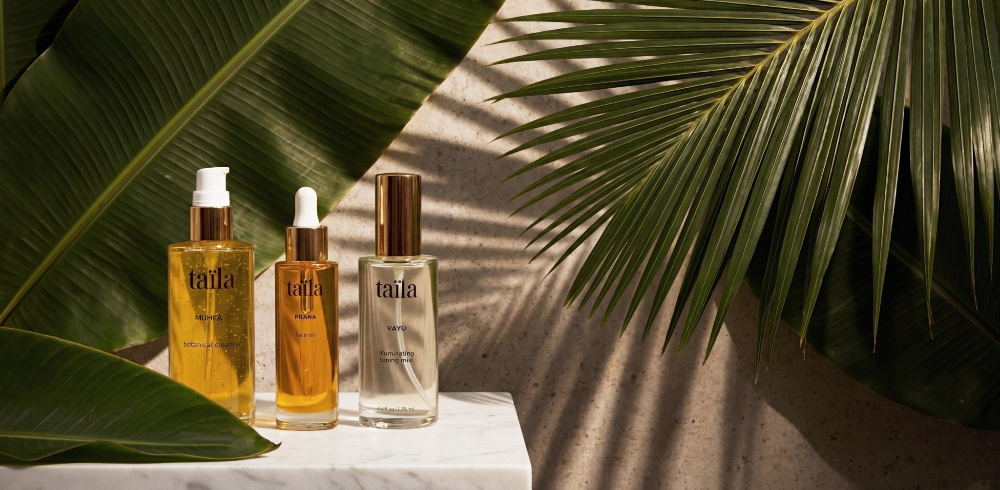 An exquisite display of the full taïla luxury Ayurvedic skincare collection arranged among lush, vibrant natural foliage, showcasing our high-performance botanical oils, mists and restorative skin rituals.