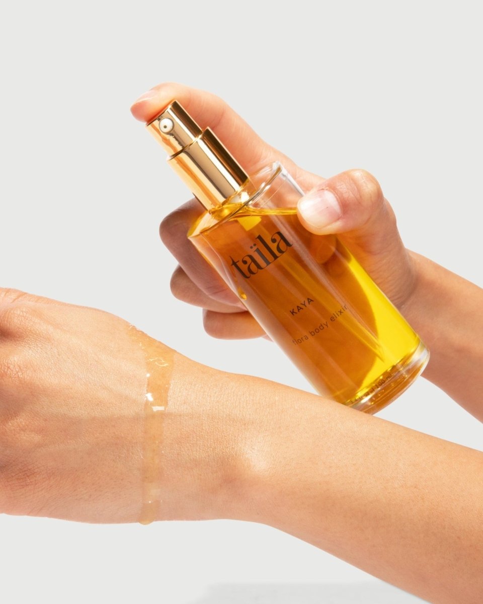 A hand gently holding the taïla Kaya Flora Body Oil Elixir bottle, showcasing a luxurious natural skincare application ritual.