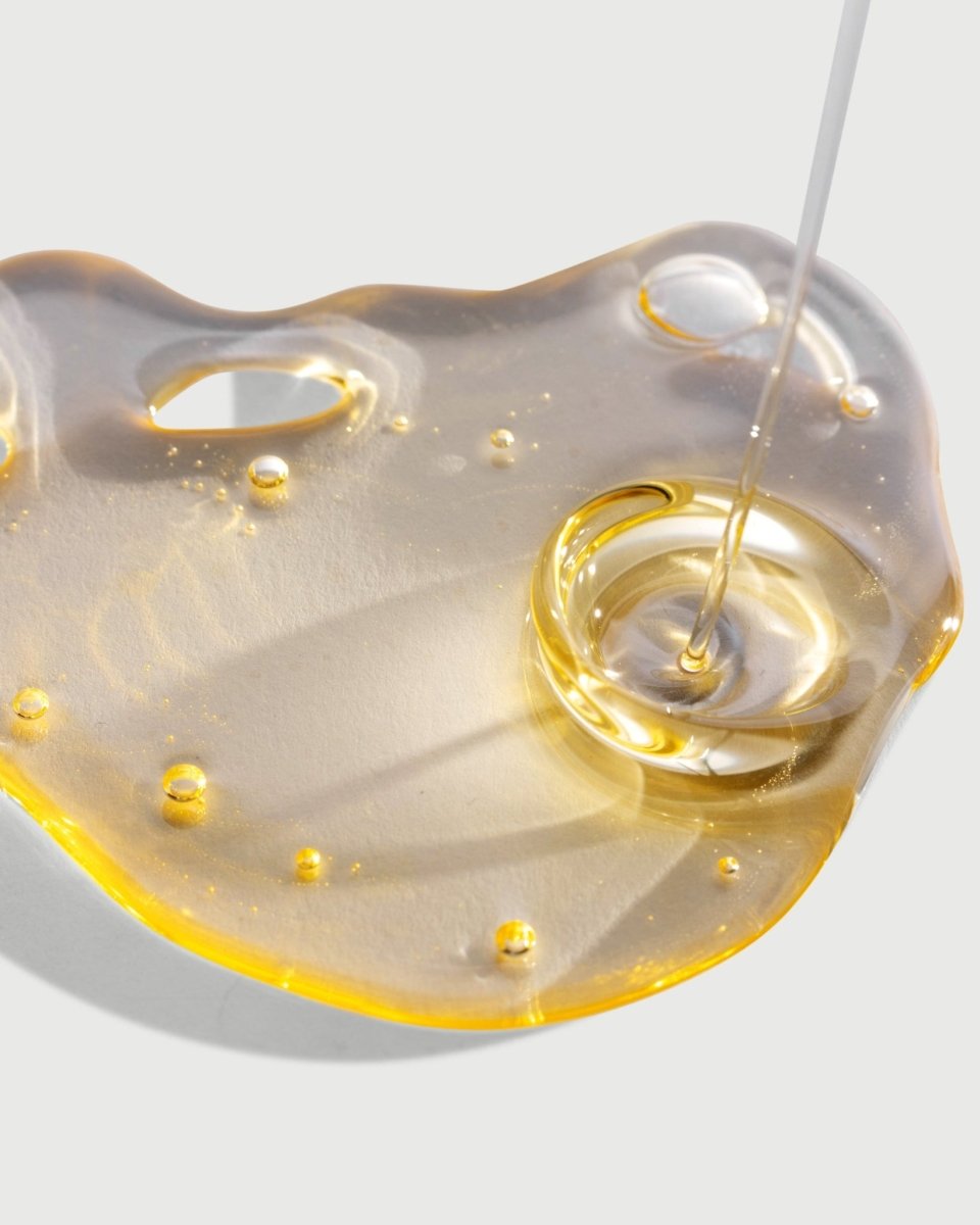 A rich close-up of the golden, lightweight texture of taïla Kaya Flora Body Oil Elixir, highlighting its smooth absorption.