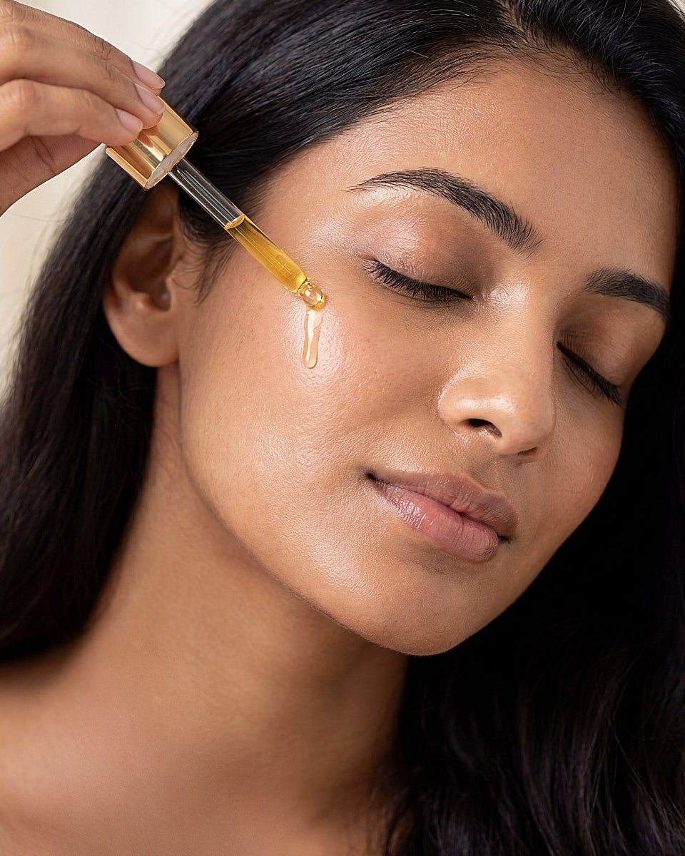 Precision glass dropper applying golden taila Prana Face Oil to cheekbones for whole-plant Ayurvedic anti-aging results, barrier repair and radiant elasticity.
